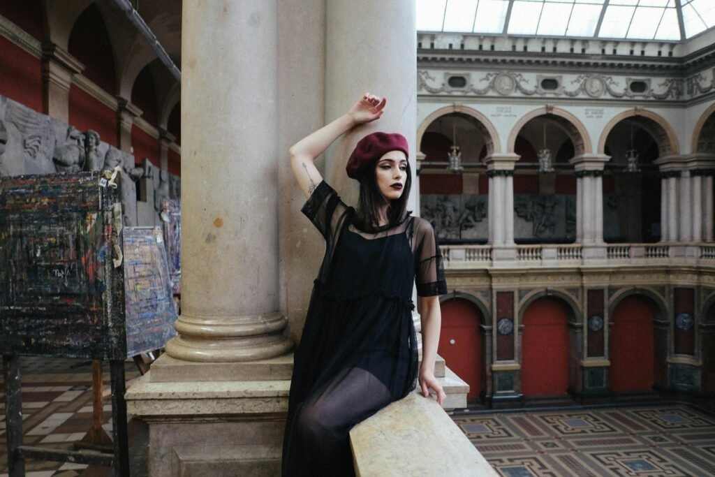 A woman poses elegantly in a sophisticated gothic style dress.