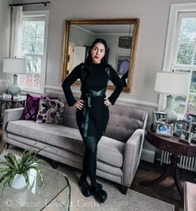 Woman stands with her hands on her hips wearing a romantic goth outfit.